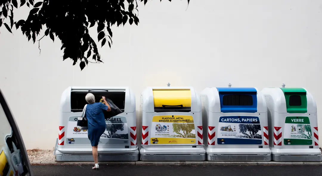 Recycling bins with a woman throwing away a bag